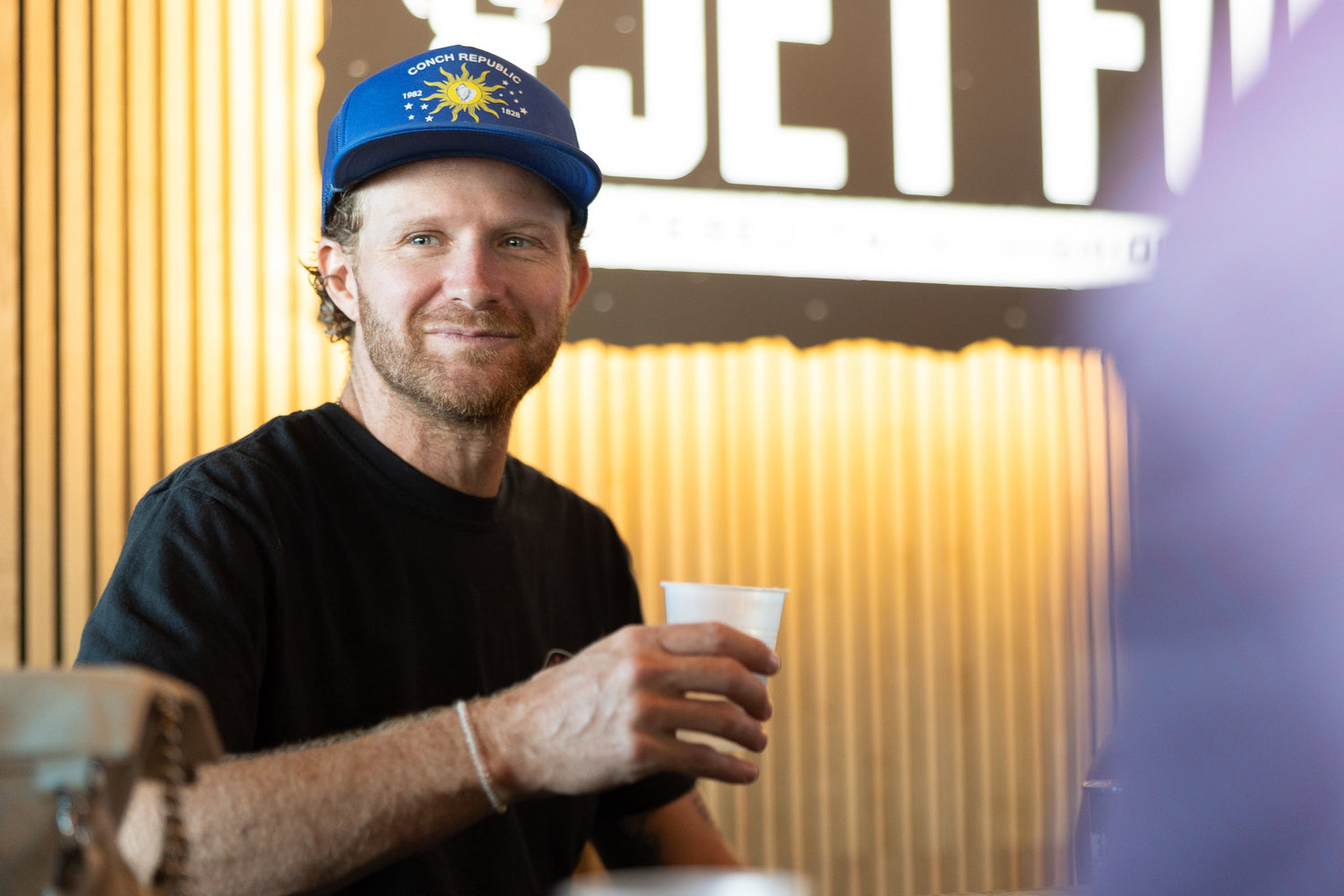 Man holding a cup in a casual setting with a blurred background